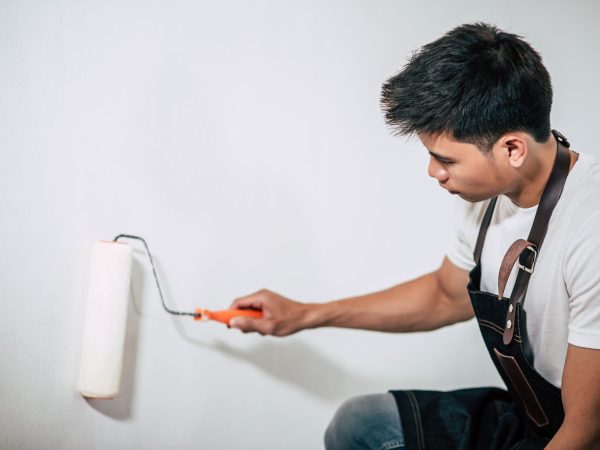 A carpenter holds a paintbrush and paints wood. Selective focus.